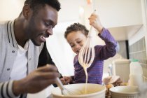 Père afro-américain préparant la nourriture avec son fils — Photo de stock