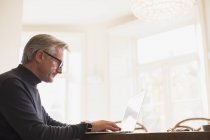 Mature male freelancer working at laptop at home — Stock Photo