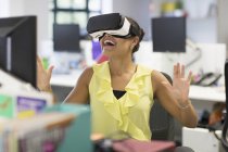 Enthusiastic businesswoman using virtual reality simulator glasses in office — Stock Photo