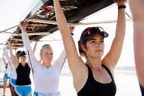 Confident, determined female rowing team lifting scull overhead — Stock Photo