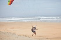 Male paraglider running on ocean beach — Stock Photo
