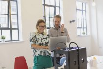 Diseñadores que utilizan el ordenador portátil en la impresora 3D en la oficina - foto de stock