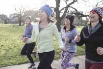 Corredores femininos confiantes correndo no parque ensolarado — Fotografia de Stock