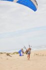 Gleitschirmfliegerin mit Fallschirm am Strand — Stockfoto