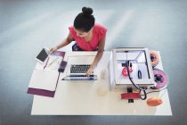 Diseñadora femenina en laptop junto a impresora 3D - foto de stock