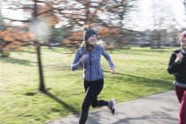 Sorrindo, corredora feminina confiante correndo no parque ensolarado — Fotografia de Stock