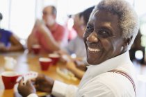 Портрет щасливий старший чоловік грає карти з друзями в громадському центрі — стокове фото