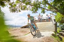 Man mountain biking down sunny obstacle course ramp — Stock Photo