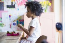 Vista lateral de la niña afroamericana comiendo gofres en la cocina - foto de stock