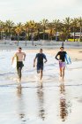 Entusiastas surfistas masculinos correndo em surf na praia do oceano — Fotografia de Stock