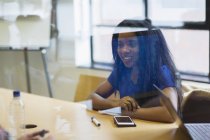Lächelnde junge Geschäftsfrau mit Smartphone hört bei Treffen zu — Stockfoto