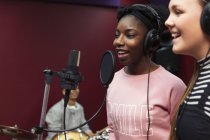 Teenage musicians recording music, singing in sound booth — Stock Photo