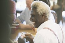 Happy senior man playing cards in community center — Stock Photo