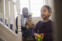African american father with two kids on staircase — Stock Photo