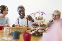 Happy senior friends enjoying afternoon tea desserts in community center — Stock Photo