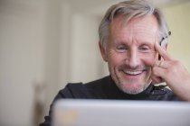 Sorrindo maduro masculino freelancer trabalhando no laptop — Fotografia de Stock