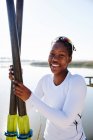 Portrait de rameuse souriante et confiante tenant des rames au bord du lac ensoleillé — Photo de stock