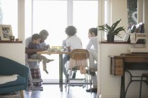 Молодая семья в пижаме раскрашивает за обеденным столом — стоковое фото