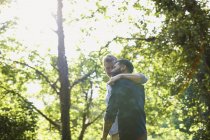 Affectionate gay couple hugging and walking in sunny park — Stock Photo