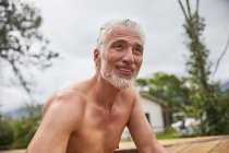 Retrato sorrindo, homem maduro confiante na banheira de hidromassagem ensolarado deck de verão — Fotografia de Stock