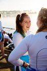 Female rowers smiling and talking at sunny lakeside — Stock Photo
