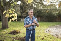 Retrato de homem caucasiano maduro confiante trabalhando com ancinho no jardim — Fotografia de Stock