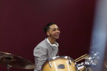 Happy teenage boy musician playing drums in sound booth — Stock Photo