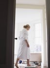 Mature woman in bathrobe stepping on bathroom scale — Stock Photo