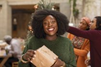 Портрет улыбается, уверенная молодая женщина держит рождественский подарок — стоковое фото