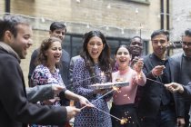 Друзі святкують з жінкою, яка тримає торт на день народження — стокове фото