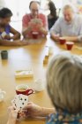 Senior friends playing cards at table in community center — Stock Photo