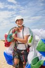 Smiling mature male paraglider carrying equipment and parachute — Stock Photo