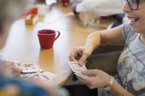 Senior woman playing cards with friend in community center — Stock Photo