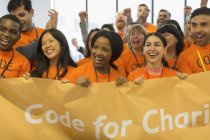 Happy hackers with banner coding for charity at hackathon — Stock Photo