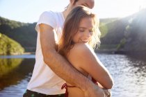 Casal afetuoso abraço no ensolarado lago de verão — Fotografia de Stock