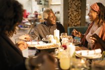 Familia multigeneracional cogida de la mano, rezando en la cena de Navidad - foto de stock