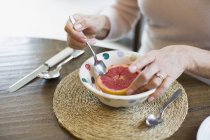Женщина ест грейпфрут ложкой, вид крупным планом — стоковое фото