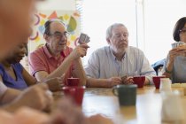 Senior friends playing cards and drinking tea in community center — Stock Photo