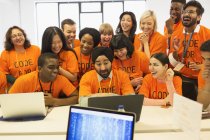 Hackers felices compartiendo laptop, codificando para caridad en hackathon - foto de stock