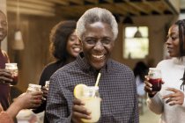 Retrato sonriente, confiado hombre mayor bebiendo limonada con la familia - foto de stock
