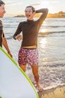 Мужчины-серферы смеются на солнечном пляже океана — стоковое фото