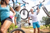 Carefree friends carrying mountain bikes — Stock Photo