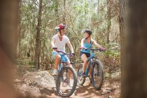 Father and daughter mountain biking on trail in woods — Stock Photo
