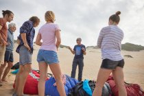 Instructeur de parapente masculin parlant aux étudiants sur la plage — Photo de stock