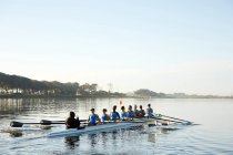 Female rowers rowing scull on lake below blue sky — Stock Photo