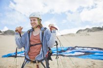Lächelnder, selbstbewusster Gleitschirmflieger mit Fallschirm am Strand — Stockfoto