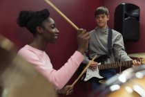 Підліткові музиканти записують музику, грають на гітарі та барабанах у звуковій кабіні — стокове фото