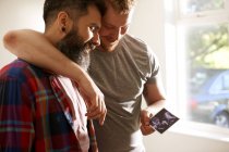 Affettuoso maschio gay coppia guardando ultrasuoni foto — Foto stock