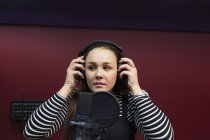 Teenage girl musician recording music, singing in sound booth — Stock Photo