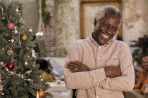 Retrato sonriente, hombre mayor seguro junto al árbol de Navidad - foto de stock